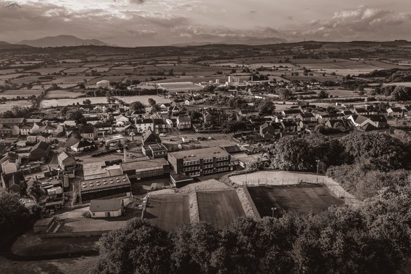 Aerial shot over Cumbrian town with fields and mountains in background. Sepia toned