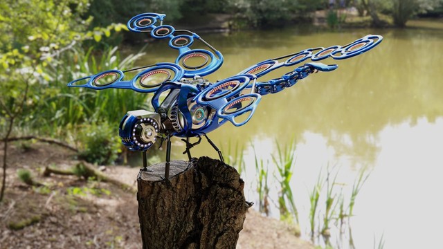 robot dragonfly resting on a tree stump by a lake