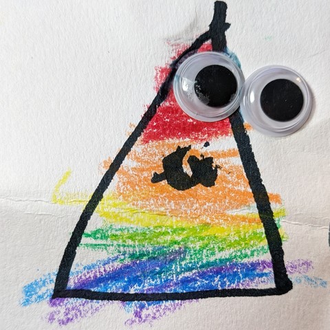 A hand-drawn rainbow triangle with googly eyes attached and a little squiggly smile in black marker.