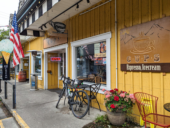 Outside a sidewalk coffee shop (Cups) in Poulsbo, WA. A bicycle is leaning on an outside table.