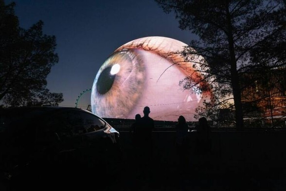 An image of a giant eye. Some people watching it