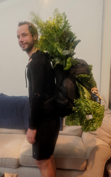 Me with a backpack with a lot of green leaves poking out the top and sides