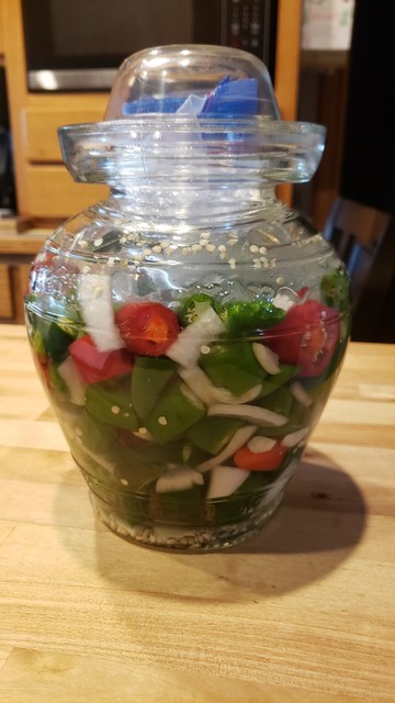 Chopped peppers, onions, and garlic in a Chinese pickling jar.