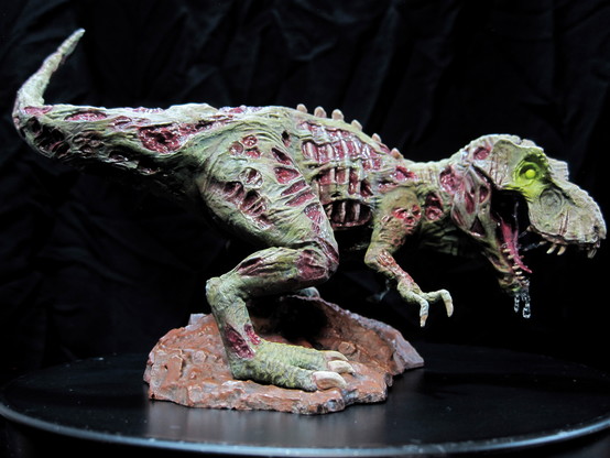 A painted miniature of a zombie t-rex dinosaur. On a black background. Right view.
