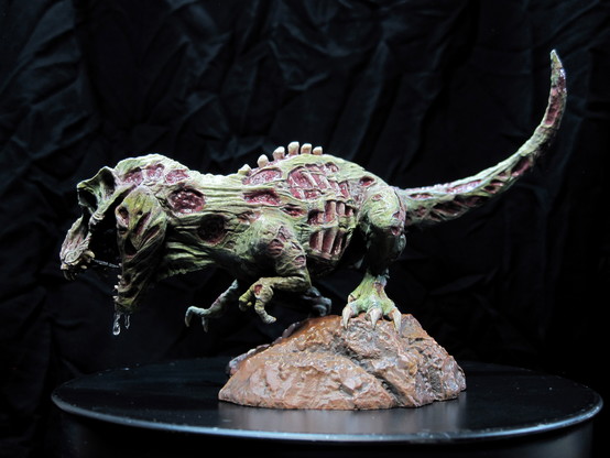 A painted miniature of a zombie t-rex dinosaur. On a black background. Left view.