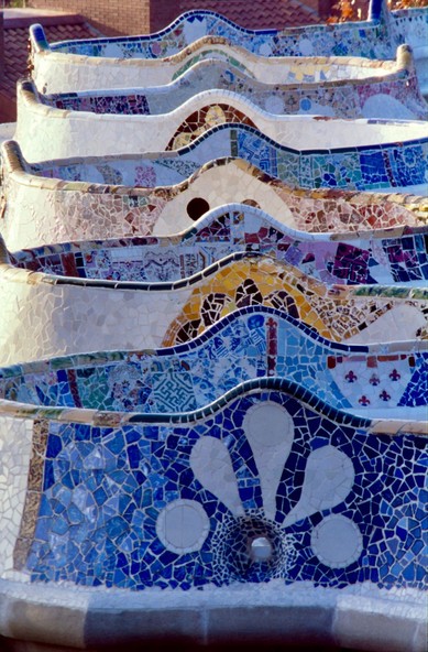 Vertical image of tiles covered benches at Parc GÃ¼ell in Barcelona, Spain. The photo has been taken with a telephoto lens and along the ax of the swinging line of the benches.