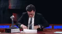Gif of Stephen Colbert (white man in a suit) frantically leafing through a stack of papers.