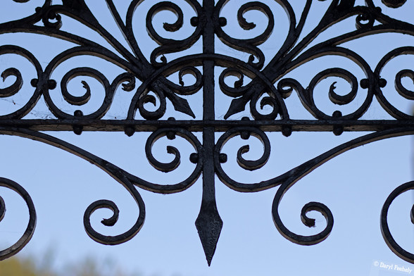 A decorative cast iron overhead piece with a point in the middle