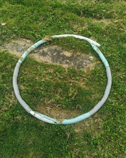 Litter. A plastic hoop lying on green grass.