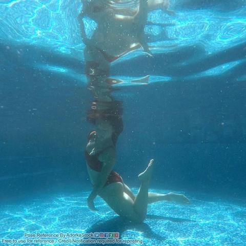 An underwater photo of a woman cascading down from the surface, one knee hitting the bottom of the pool. She is arched in a C shape, and she is reflected on the underside of the surface above her.