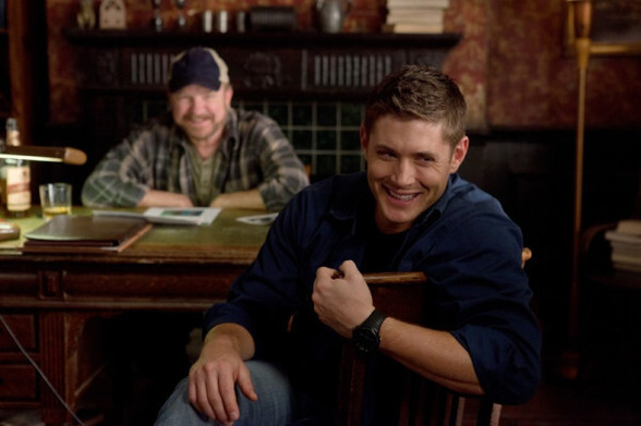 Dean And Bobby smiling (they are sitting at Bobby's desk at his home)