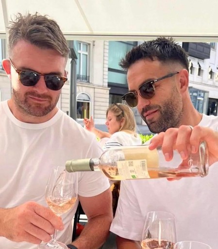 A picture of Irish International and Munster scrum half Conor Murray pouring a glass of RosÃ© for Irish International and Munster Flanker Peter O'Mahoney. They're both wearing sunglasses.
