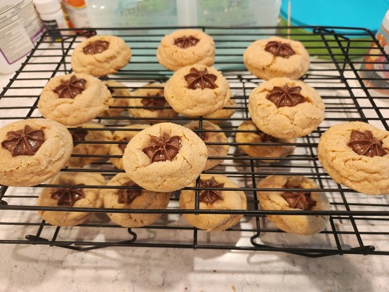 Two layers of cooling racks filled with peanut butter cookies with chocolate stars pressed in them