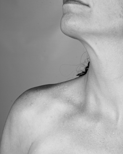 photo of a woman's clavicle from the upper arm and the line curves up her neck to her lips