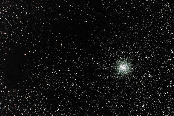 A globular cluster of stars in the lower right and a section of space that is starless in the upper left.