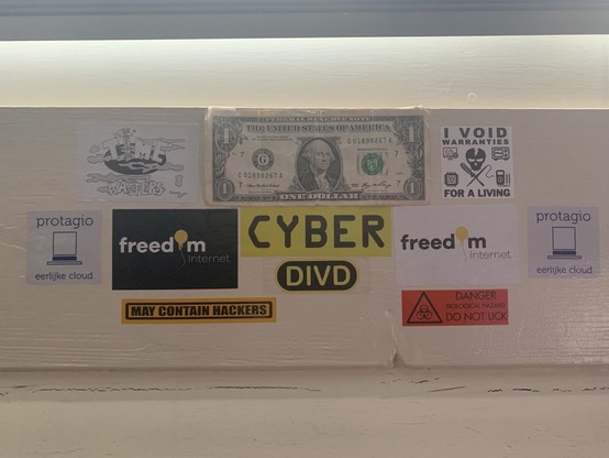 A collection of hacker related stickers and a one dollar bill.