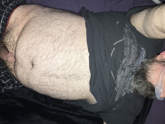 Cock out of pantsâ€™ waistband, exposed tum tum from lifted shirt just covering chest, grey beard underneath cpap nose pillow.