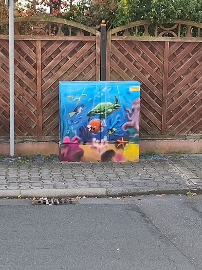 Someone Painted an unser the SEA Scene with a Turtle and some Reef and fish on a Public Box where wires Run through for Internet