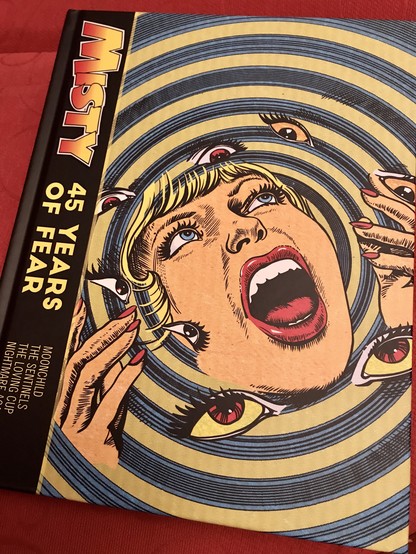 The front cover of the hardback Misty comics book, showing a girl’s head and hands among a swirling psychadelic set of circles.