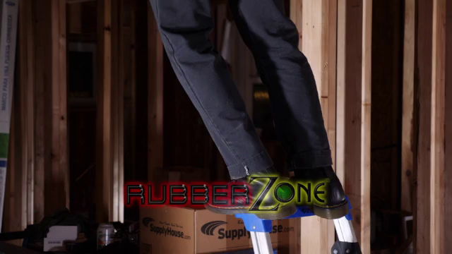 Montage of clips showing two electricians in a raw-framed house under construction getting into orange hi-viz latex gear and with the dom chaining the  sub to a scaffold, muzzling him, and playing with chastity, electroshock toys, and a vibrating butt plug. At the end of the clip, the RubberZone logo and the source video title, "The Electricians" are displayed.