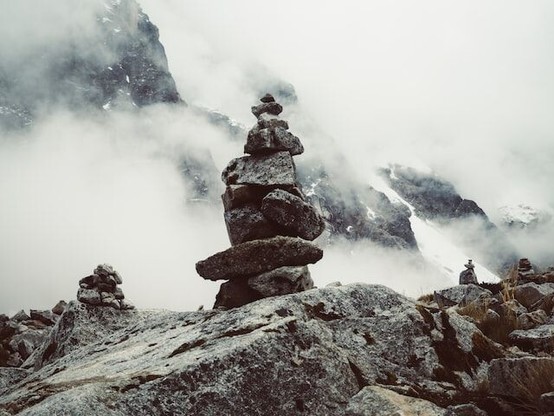 A pile of rocks balancing on one another, set against a misty storm in the background.