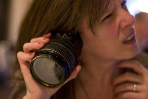 Do conference attendees know what they want? Photograph of a puzzled woman holding a camera lens to her ear.