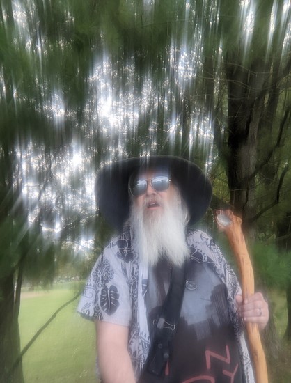 blurry image of middle aged man with grey beard and gandalf style hat and staff