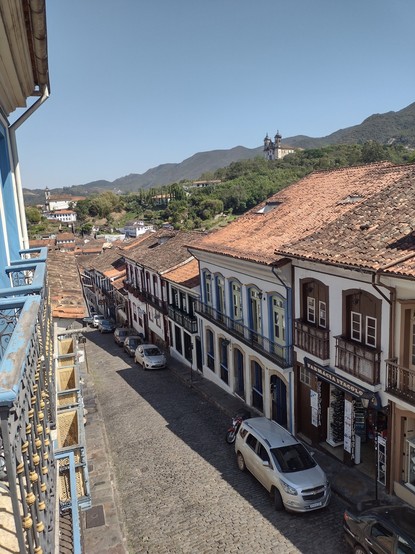 Looking down a street in Ouro Preto. Mountains and a historic church in the background.
