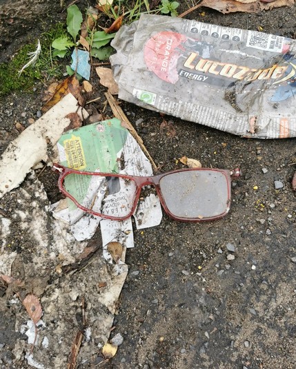 Litter. A broken pair of glasses. Just the frames with one lens missing. Surrounded by other bits of litter.
