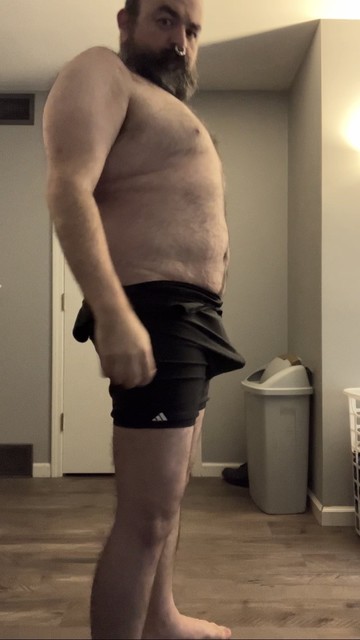 Singlet down around my waist showing bare bear torso and tummy with full erect bulge jutting against the stretch fabric