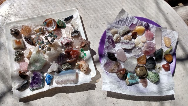 Two plastic trails with sorted crystals and gems on them, sunbathing after I clean them.
