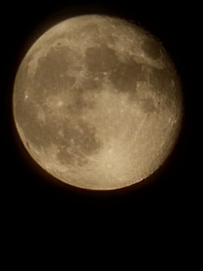 Closeup of a golden, almost full moon in the night sky.