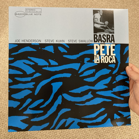Album cover for Basra by Pete La Roca, featuring an abstract piece of art, what looks like broken shards of blue glass on a black background