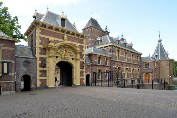 photograph of entrance showing ornate archway, cobblestones are underfoot, there are spires of buildings sticking up in the background