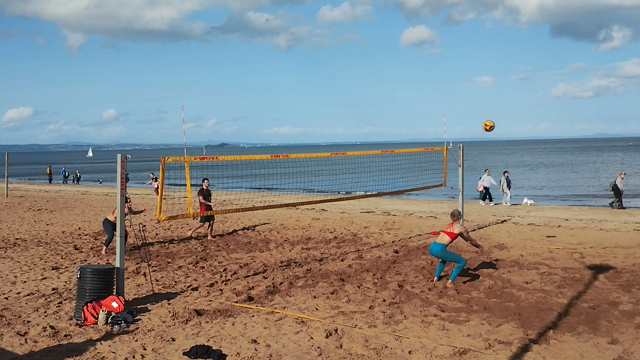 Two men and two women playing beach volleyball in bright, warm, autumn sunlight on Portobello Beach