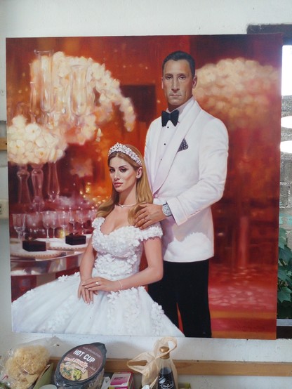 wedding portrait of a couple from Ukraine, she has blonde hair, there are glasses and chandeliers behind them, he has his hand on her shoulder, he is strong looking and wearing a white tuxedo
