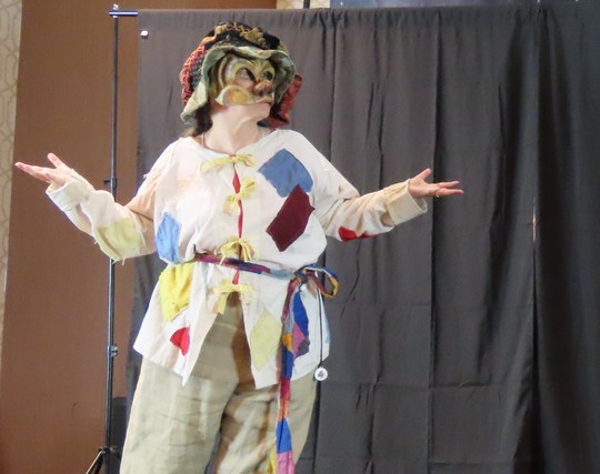 An actor performs a commedia dell'arte play as the stock character Arlecchino in colorful patchwork.