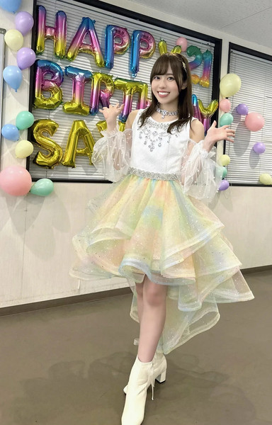 Sakuri posing in her stage outfit, smiling with baloons in the background saying Happy Birthday Sayuri.