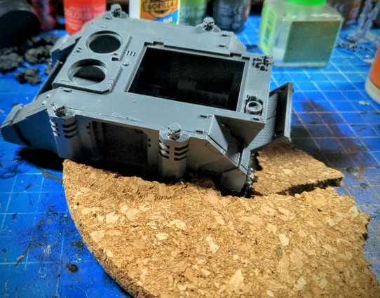 Rhino transport tank by Games Workshop crashed on a cork base waiting for a Knight Tyrant to step on it.