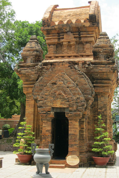 photo of a small temple , ornate stone design work all over it, it is strong and built with lots of bricks and stones fitted together, it is sienna brown colored