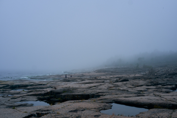 A very foggy beach with silhouettes of two people in the distance