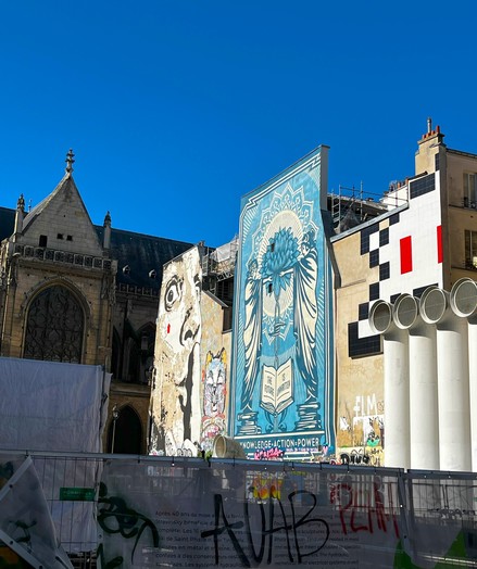 Large works of graffiti adorn the walls of modern buildings, with an ancient church next door.