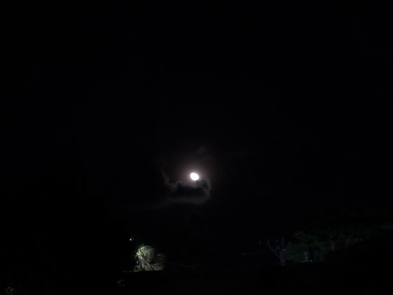Fotografía nocturna de la luna atraída por un brazo de nube oscura hacia la porción más grande de oscuridad de la escena.