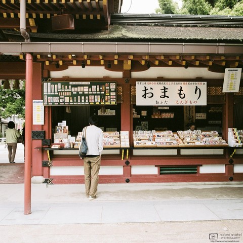 This photo shows a stand inside the shrine selling Omamori. Omamori are amulets that are said to provide various forms of luck or protection – in the case of Dazaifu Tenmangu, a variety of education-themed talismans focusing on successful studies or luck in passing exams are available.