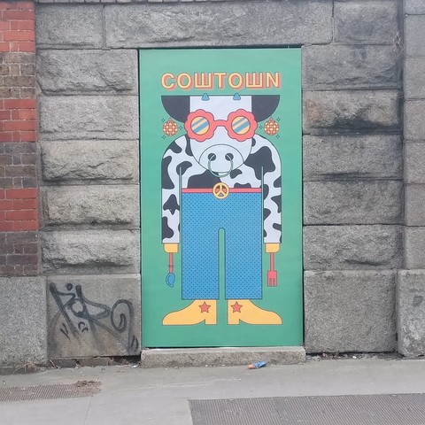 Mural outside Cowtown food van in Stoneybatter. It's a cartoon cow wearing boots, jeans, sunglasses, belt with peace symbol