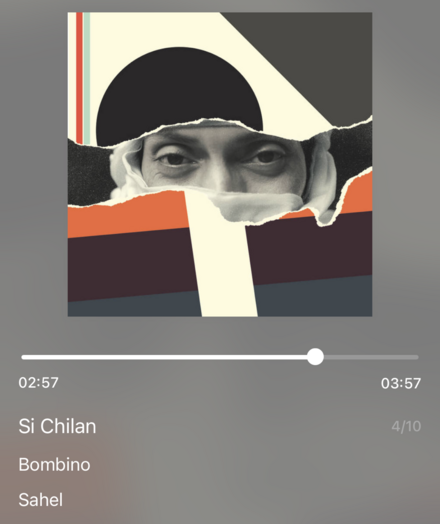 The app on my phone shows that I am listening to a Bombino’s album called “Sahel”. The song is called “Si Chilan”. The main picture is a man looking through a torn abstract print, and is black, grey, cream, and orange. The man’s eyes are the main feature.
