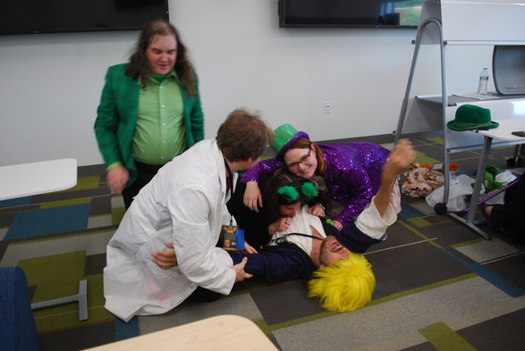 After performing anime parody plays in a college classroom during an anime convention five actors are in a hug pile on the floor; the one on the bottom is dressed as a parody of a Super Saiyan from "DragonBall Z" and on top of him are an anime cat girl, an anime magical girl, an anime perverted teacher, and an anime school boy.