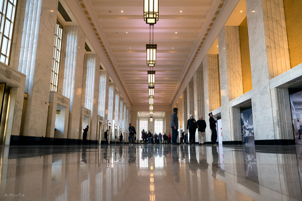 A color photograph in the lobby of the Old Main Post Office during Open House Chicago 2018. Pictured is a symmetrical photo of the art deco lobby taken from floor level.