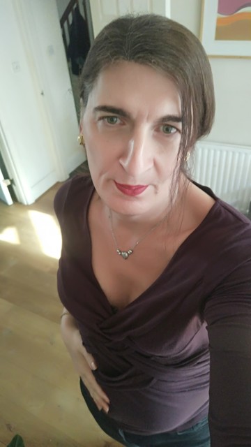 A selfie of a brunette trans woman in a wine colored top