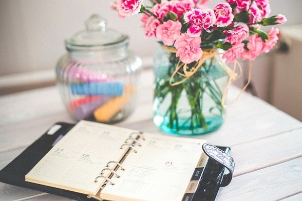 open organizer on a table with a vase of pink carnations